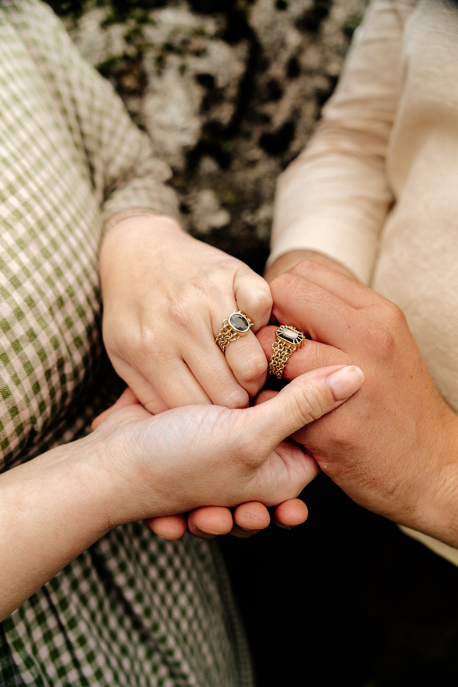 Gold rings featuring a large blue and yellow parti sapphire centrepiece, a green sapphire centrepiece both surrounded by a chain link chainmail band with white gold accents. 
