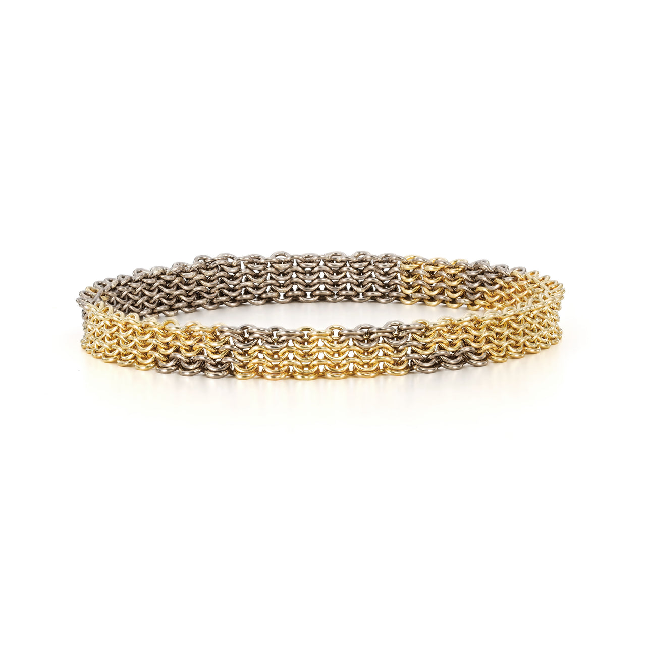 A yellow and white gold chain link bracelet made of handmade links woven with geometric patterns to create a chainmail bangle. on a white background.