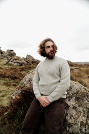 Mens jewellery male modelling a white gold necklace with white gold and yellow gold detail chainmail pendant. A blue slender rectangle sapphire sits on the left hand side if the chain in a yellow gold rub over setting
