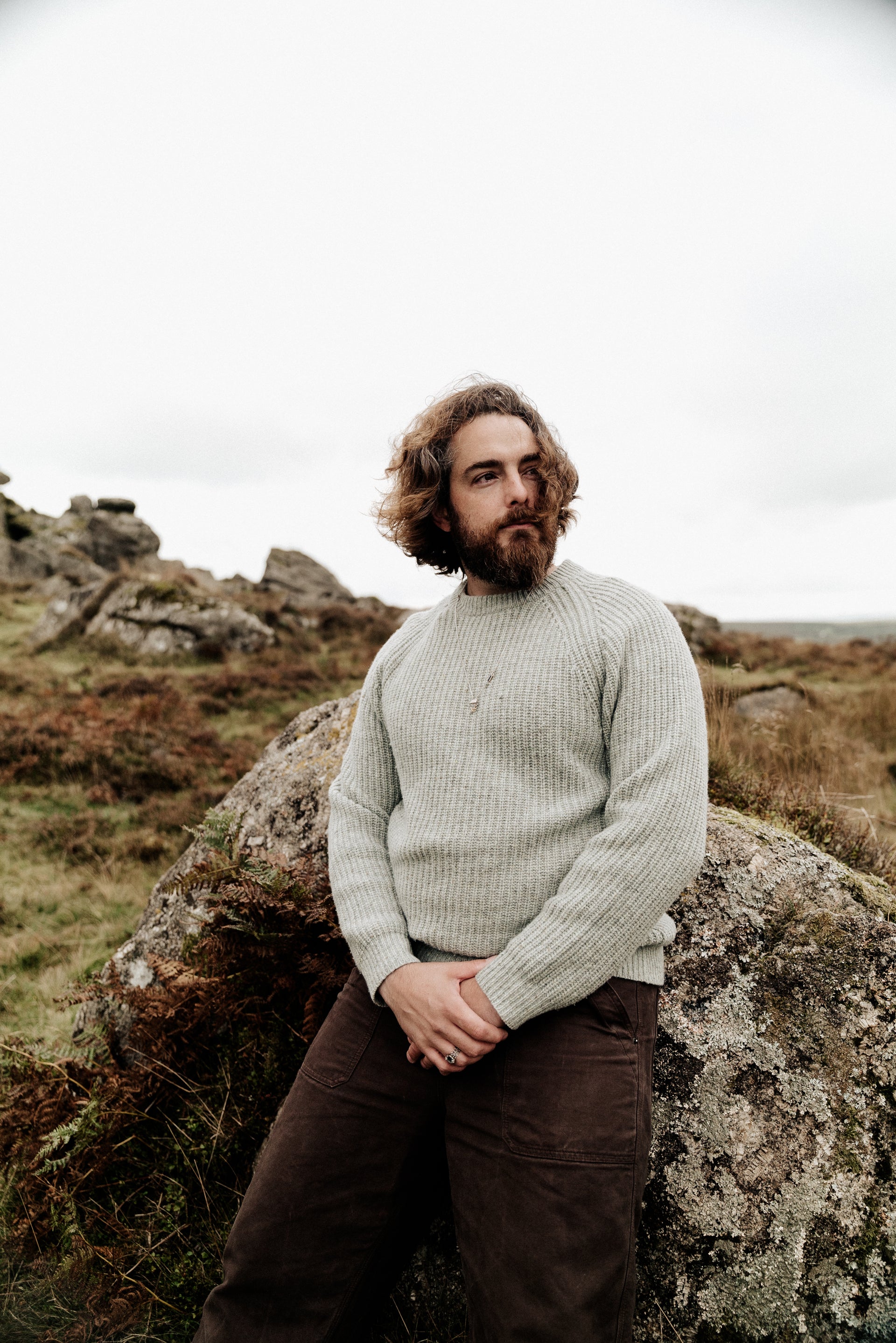 Mens jewellery male modelling a white gold necklace with white gold and yellow gold detail chainmail pendant. A blue slender rectangle sapphire sits on the left hand side if the chain in a yellow gold rub over setting