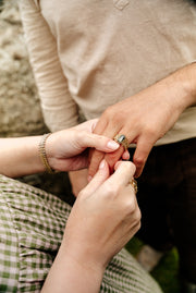 A gold ring featuring a large blue, green and yellow parti sapphire centrepiece, surrounded by a chain link chainmail band with white gold accents. 