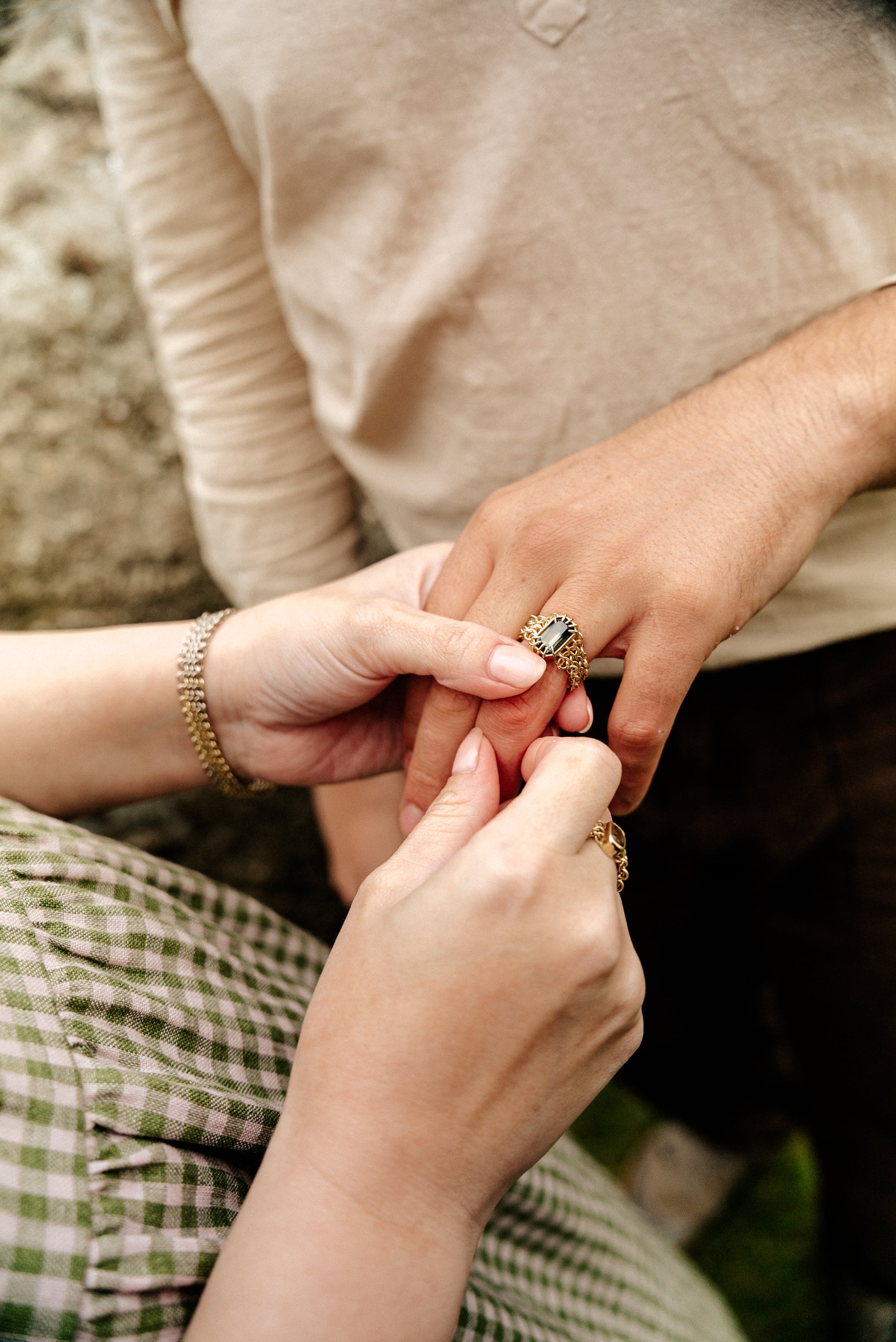 A gold ring featuring a large blue, green and yellow parti sapphire centrepiece, surrounded by a chain link chainmail band with white gold accents. 