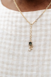 A solid gold necklace with a square-cut Australian Parti Sapphire pendant and three dangling diamonds, worn on a checkered white background.