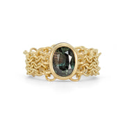 An 18ct yellow gold chain link ring featuring a large green oval natural sapphire gemstone, with intricate chainmail-like links making up the band.