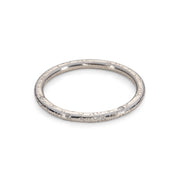 A 'Dartmoor' wedding band platinum ring with round SI flush set brilliant cut diamonds on a band. circle texture on a round band, scattered diamonds. on a white background