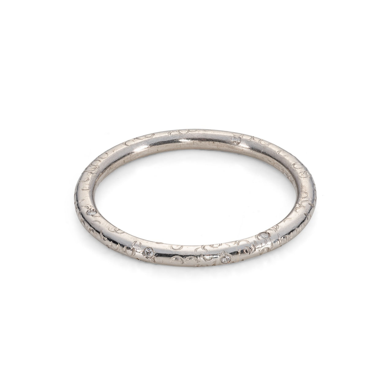 A recycled white gold halo round wedding band textured ring with diamonds in the band scattered effect delicate ring on white background